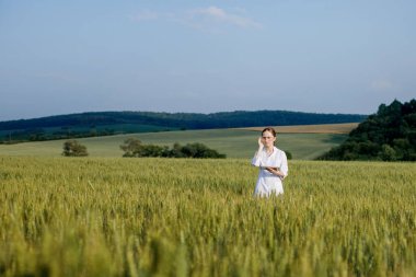 Tarımsal faaliyetlerde modern teknolojilerin uygulanması için ekili buğday tarlasında dijital tablet bilgisayar kullanan laboratuvar teknisyeni..