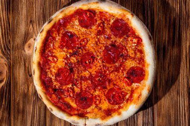 Domates soslu pizza, mozzarella, salam, kırmızı biber, ahşap kaplama bal. Yukarıdan görüntüle.