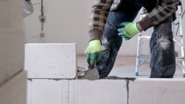 İnşaatçı duvar inşaatı sırasında bloğu yerleştirir.