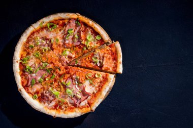 Mozarella peynirli, jambonlu, siyah arka planda domates soslu lezzetli pizza. Boşluğu Kopyala.