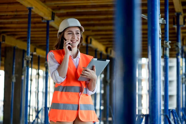Female construction engineer. Architect with a tablet computer at a construction site. Young Woman looking, building site place on background. Construction concept.
