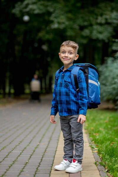 Portrait of a first grader with a backpack. The boy goes to school.