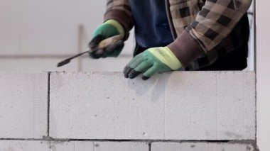 İnşaatçı duvar inşaatı sırasında bloğu yerleştirir.
