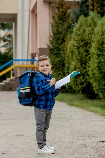 快乐的学童 穿着休闲装 背着背包 在笔记本上写着便条 在校园里 — 图库照片