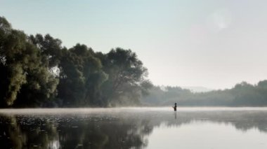 Sisli bir yaz sabahında akıntıda balık yakalayan bir balıkçı. Dönerken balık tutmak.
