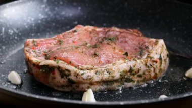 Meat steak is fried in rosemary oil and garlic in a frying pan