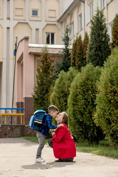 年轻的母亲看着孩子上学 然后在告别时拥抱 — 图库照片