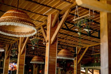 Wicker straw lamps, wooden roof. Trendy interior design of a hipster cafe in loft style.