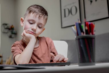 Boy sitting at the table, studying mathematics, got tired and leaned on his hand