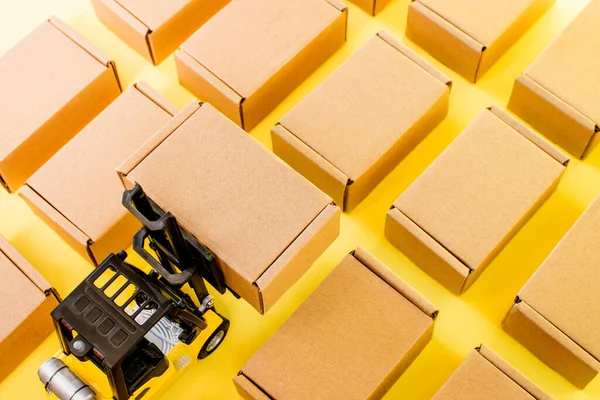 Forklift truck raises cardboard boxes on a yellow background. Cargo sorting concept.