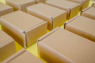 Sarı arka planda bir sürü karton kraft kutusu var. Paket paketleniyor