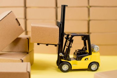 Forklift kamyonu sarı arka planda karton kutular kaldırıyor. Kargo sıralama kavramı.