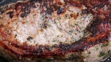 Meat steak is fried in rosemary oil and garlic in a frying pan