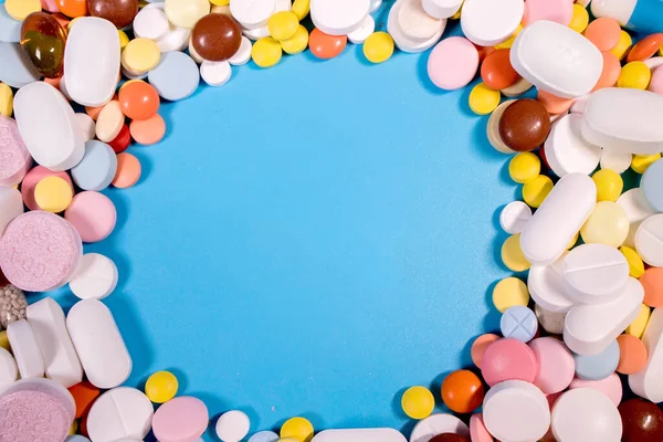 Frame with colorful pills and capsules on a blue background. Place for text.