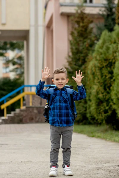 穿着蓝色衬衫的快乐淘气的学童摆出一副手势 回学校去 — 图库照片
