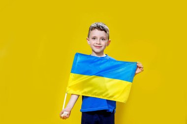 Sarı ve mavi bayrak taşıyan, Ukrayna bayrağı taşıyan küçük bir çocuk. Çocuk Ukrayna bayrağını göstererek Ukrayna 'yı destekleyecek. Rus saldırısı Ukrayna 'da. Savaşa karşı çocuklar.