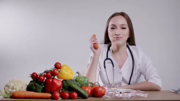 营养师吃胡萝卜 并为病人规定健康的饮食 一位营养学家为病人的健康开了药方 — 图库视频影像
