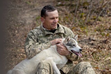 Beyaz köpekli Ukrayna askeri üniformalı bir adam..