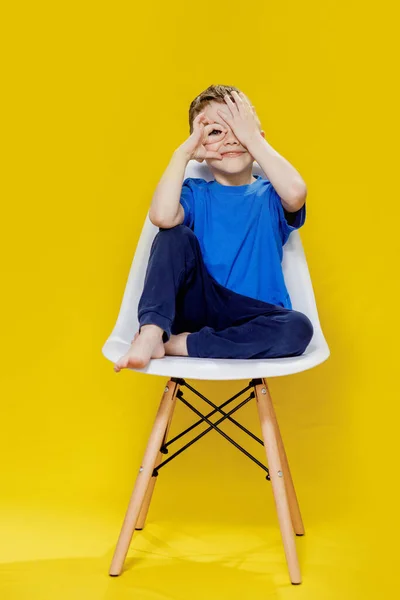 stock image Cheerful Little Boy Sitting on Yellow Chair - Bright and Playful Portrait.