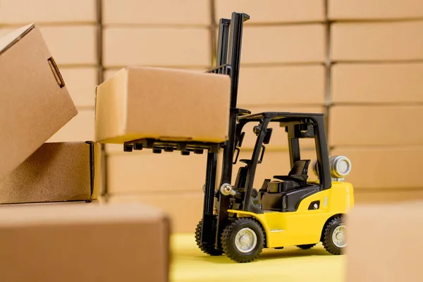 Forklift truck raises cardboard boxes on a yellow background. Cargo sorting concept.
