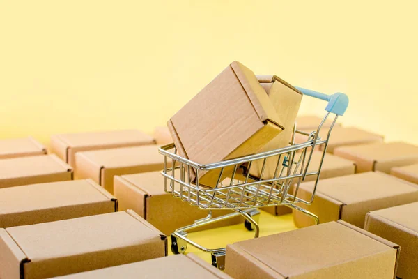 Shopping cart with boxes on a yellow background. The concept of sales, discounts, online shopping and delivery