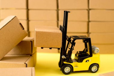 Forklift kamyonu sarı arka planda karton kutular kaldırıyor. Kargo sıralama kavramı.