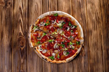 Vegan pizza with tomato sauce, cherry tomatoes, mushrooms, broccoli, red onion on wodenbackground. View from above.