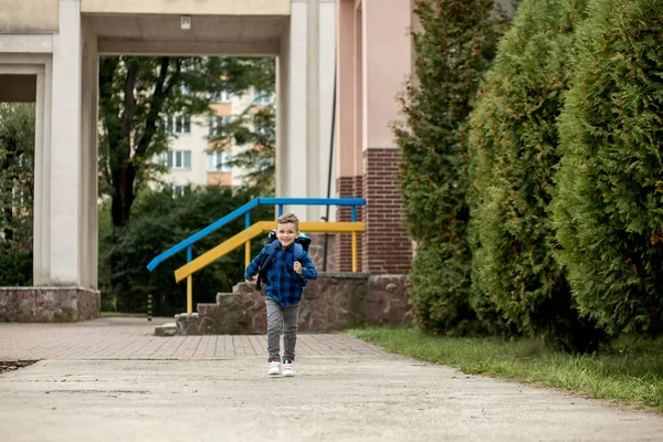 バックパック付きの小さな1年生は学校から家に帰る — ストック写真