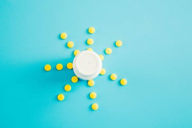 Mavi arka planda sarı haplardan ve şişeden bir güneş..