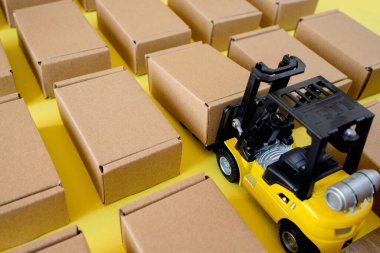 Forklift kamyonu sarı arka planda karton kutular kaldırıyor. Kargo sıralama kavramı.
