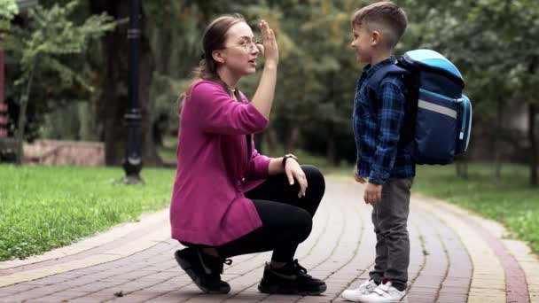 在上学的路上 年轻的母亲抱着兴奋的一年级儿子 准备好学了 — 图库视频影像