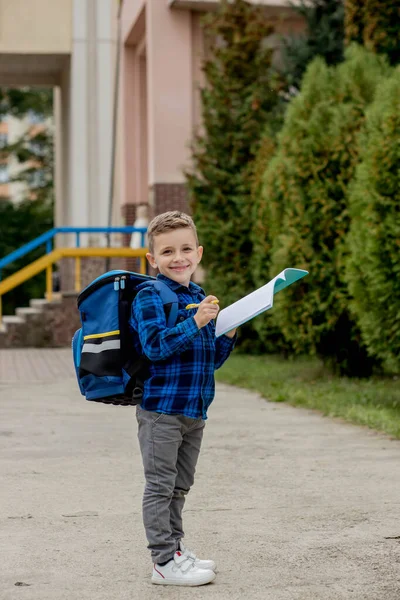 快乐的学童 穿着休闲装 背着背包 在笔记本上写着便条 在校园里 — 图库照片