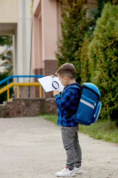 Ein Kleiner Schuljunge Blickt Durch Eine Lupe Auf Ein Lehrbuch — Stockfoto