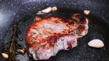 Şef, biberiye ve sarımsaklı tavada sulu et pişiriyor, mutfak gereçleri kullanıyor. Kızarmış biftek pişirme işlemi