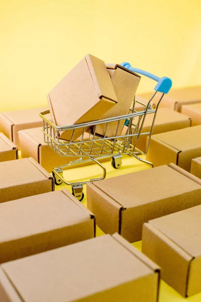 黄色背景的装有盒子的购物车 网上购物和送货的概念 — 图库照片