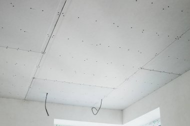 İnşaat alanında askıya alınmış tavanın kurulumu tamamlanıyor.