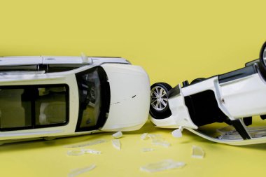 Sarı arka planda iki küçük oyuncak araba kazası, kaza, trafik kazası.