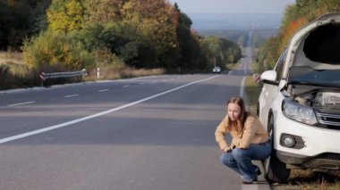 Kızgın kadın bozuk bir arabanın yanında duruyor ve direksiyonu tekmeliyor..