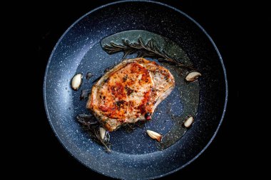 Şef, biberiye ve sarımsaklı tavada sulu et pişiriyor, mutfak gereçleri kullanıyor. Kızarmış biftek pişirme işlemi