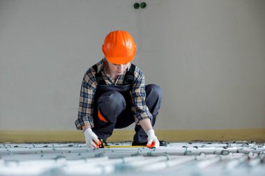 İşçi zemin altı ısıtma sistemi kuruyor. Sıcak zemin ısıtma sistemi.