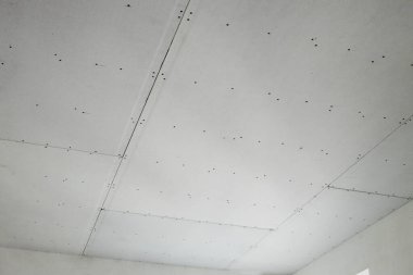 İnşaat alanında askıya alınmış tavanın kurulumu tamamlanıyor.