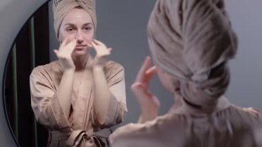 Yüz yıkama ve gülümseme için nemlendirici köpük kullanan bir kadın..