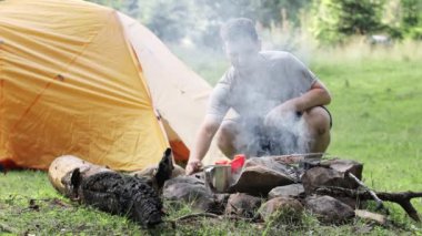 Adam çadırın yanında lezzetli bir kebap hazırlıyor. Çok dumanlı kebap pişirme süreci. Doğada yemek pişirmek.