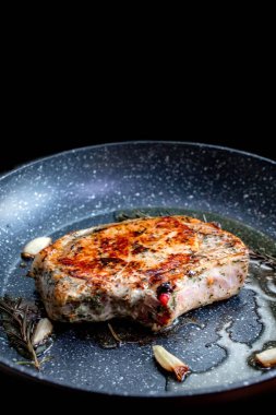 Şef, biberiye ve sarımsaklı tavada sulu et pişiriyor, mutfak gereçleri kullanıyor. Kızarmış biftek pişirme işlemi