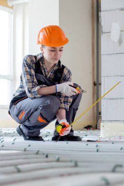 Kadın işçiler sıcak zeminin kurulumu sırasında ölçümleri alırlar. Sıcak zemin ısıtma sistemi.