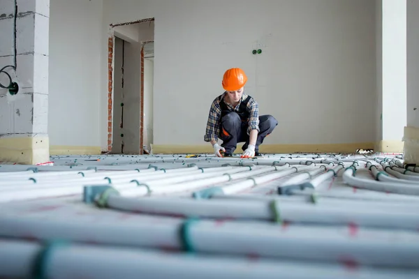 Woman worker takes measurements during the installation of a warm floor. Warm floor heating system.