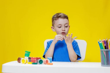 Küçük bir anaokulu öğrencisi elinde fırçayla masada oturur ve avucunu boyar. Anaokulu geliştirme