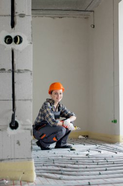 Yeraltı ısıtma sistemi kuran kadın işçinin portresi. Sıcak zemin ısıtma sistemi.