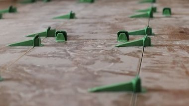 Döşeme düzleştirme sistemi, dört adet takozlu plastik yeşil şarjör. Yakın plan görünümü, seçici odak, bulanık arkaplan.