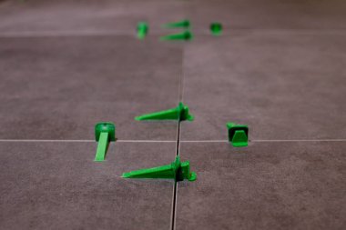 Döşeme düzleştirme sistemi, dört adet takozlu plastik yeşil şarjör. Yakın plan görünümü, seçici odak, bulanık arkaplan.